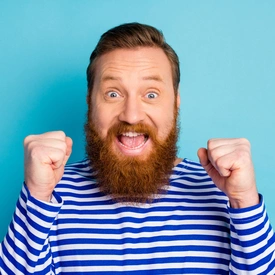 Un homme barbu les poings serrés et souriant